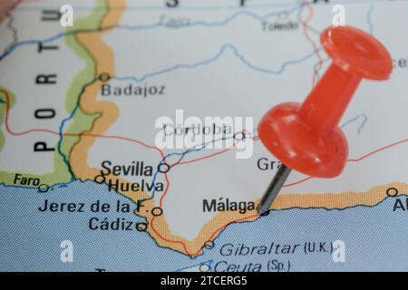 A red pin stuck into a map of Western Europe, pinpointing the location of Malaga Stock Photo