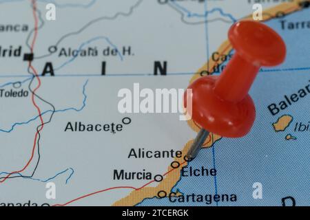 A red pin stuck into a map of Western Europe, pinpointing the location of Alicante Stock Photo