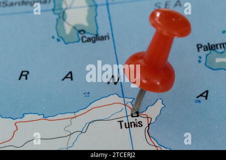 A red pin stuck into a map of Western Europe, pinpointing the location of Tunis Stock Photo