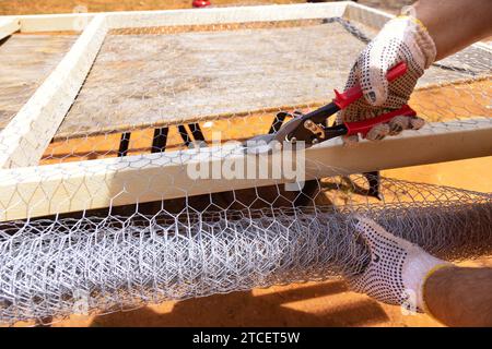 Worker uses scissors for metal to cut metal mesh Stock Photo