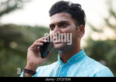 Smiling Indian man talking on phone with friend of family member Stock Photo