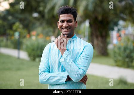 Smiling Indian man in traditional clothes attending outdoor party Stock Photo