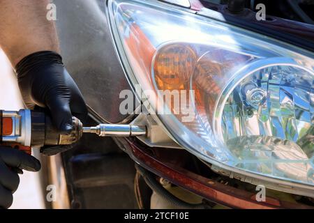 While repairing car, repairman installs headlight during car service