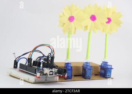 Breadboard circuit with programmable controller board and micro servo with artificial flowers attached to horn of servos demonstrating prototype Stock Photo