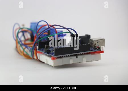 Micro controller board with jumper wires connecting breadboard and micro servos on the background. Building electronic prototype for a project Stock Photo