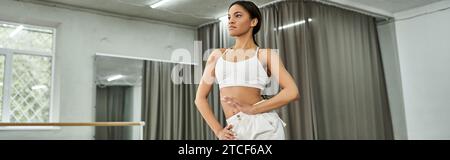 focused young african american dancer in white sportswear rehearsing in modern dance hall, banner Stock Photo