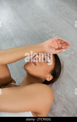 talented african american dancer with closed eyes lying down on floor while rehearsing in studio Stock Photo