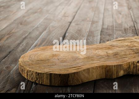 Wooden rustic cutting board isolated on wooden table. Stock Photo