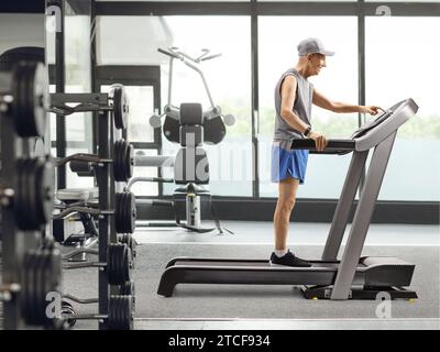 Full length profile shot of a senior man standing on a treadmill and pushing a button on display in the gym Stock Photo