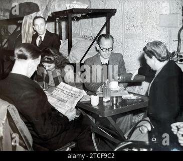 UNDERGROUND SHELTER . A husband a wife (Mr and Mrs Vangrove)  share their table  at Holborn Underground  station in July 1944  while the man at left reads about the advance on Caen. Stock Photo