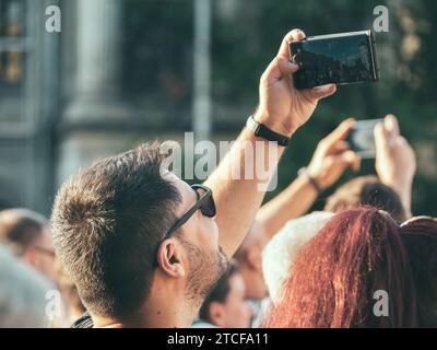 Bucharest, Romania - June 17 2023: Happy tourist man with a smartphone taking pictures in the center of Bucharest Stock Photo