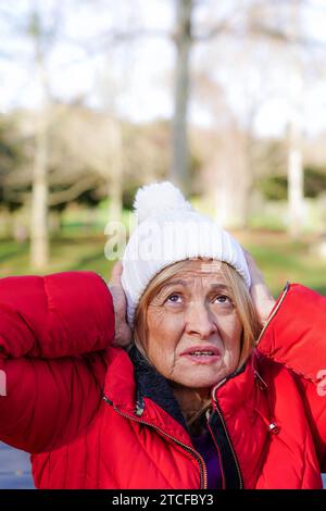 autistic mature woman looking up with headache from noise outside Stock Photo