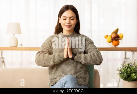 Calm young brunette woman sitting on couch, concentrating Stock Photo