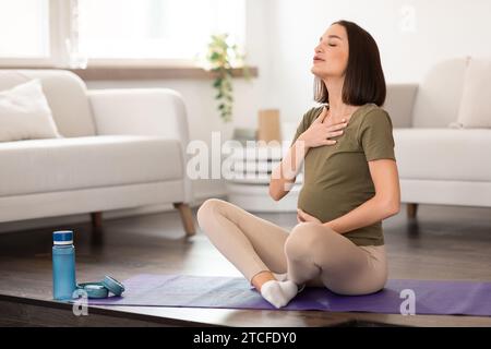 Pregnant woman practices prenatal yoga focusing on breathing exercises indoor Stock Photo