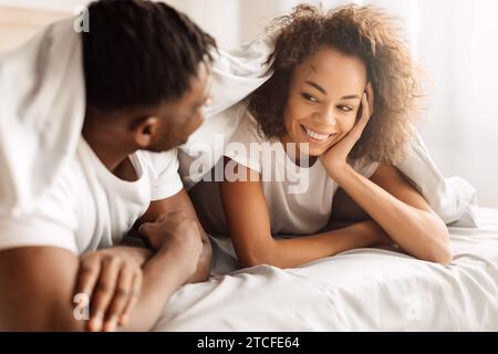 Happy Black Young Couple Lying Covered With Blanket In Bed Stock Photo