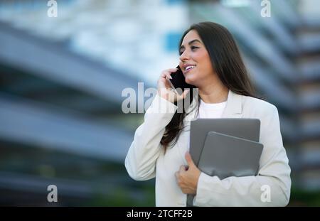 Young Arabic businesswoman talking using mobile phone standing outside Stock Photo