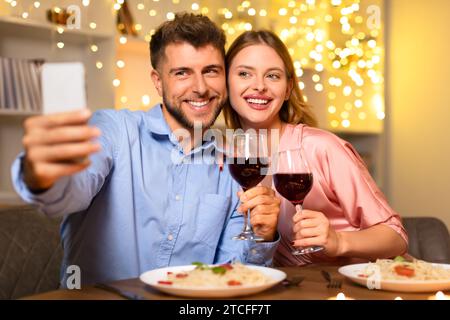 Happy couple taking selfie with wine during dinner Stock Photo
