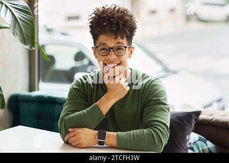 Portrait of positive cool young black man sitting at cafe Stock Photo