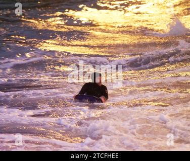 UK Weather, Rain clears and temperatures begin to drop to zero. Met office declares flood warnings across Southern England. Spectators watch from the promenade as powerful waves break. An intrepid bodyboarder is unperturbed by wind driven waves impending darkness and icy cold water at Towan beach Newquay Cornwall UK.  12th December, 2023, Robert Taylor/ Alamy Live News. Stock Photo