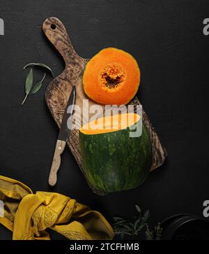 Green pumpkin on a dark background. Slice of a pumpkin next to a whole pumpkin Stock Photo