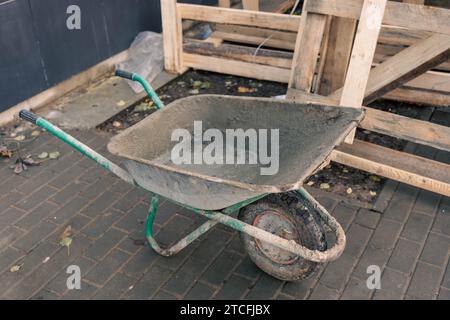 A heavy-duty construction wheelbarrow parked at a busy construction site, filled with various construction materials and tools, ready to be transporte Stock Photo