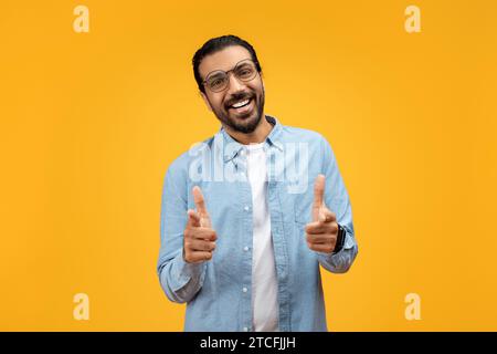 Welcoming man with glasses and a beard, pointing directly at the camera Stock Photo