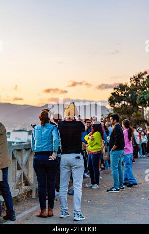 Tourists taking photos in Santa Monica, California, at sunset with the Santa Monica Mountains in the background Stock Photo