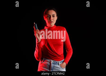 Young woman with electronic cigar on dark background Stock Photo