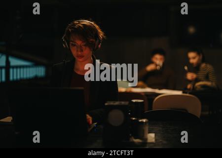 Female employee working separately from her team for business growth in corporate office, late at night. Stock Photo