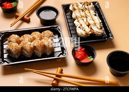 Set of sushi rolls with salmon, cream cheese, sesame seeds in a plastic package, Chinese sticks, soy sauce on a light background. Delivery of sushi Stock Photo