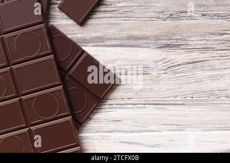 Whole bar of dark chocolate and broken chocolate on gray wooden background, top view, with space for text, chocolate background. Stock Photo