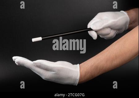 Magician hands with wand performing trick close up view Stock Photo