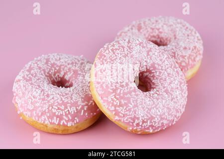 Three fresh donuts on pink background. Stock Photo