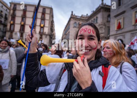 Barcelona, Spain. 12th Dec, 2023. A nurse with inscriptions on her forehead carries a plastic trumpet during the protest in Plaza de Sant Jaume. Called by a group of minority unions, thousands of nurses and administrative staff of the public health service have demonstrated in the center of Barcelona to improve their working conditions and show their rejection of the agreement between the majority unions and the administration known as the “III acord”. (Photo by Paco Freire/SOPA Images/Sipa USA) Credit: Sipa USA/Alamy Live News Stock Photo