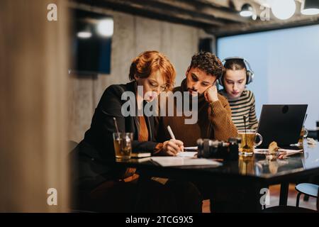 Young, business group analyzing sales data for revenue growth and marketing strategy in modern office setting, late at night. Overtime concept. Stock Photo