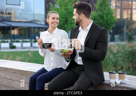 Business people eating from lunch boxes outdoors Stock Photo