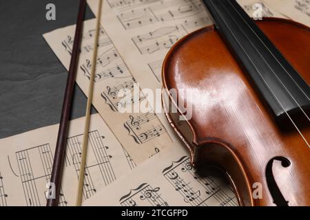 Violin, bow and music sheets on black table, closeup Stock Photo