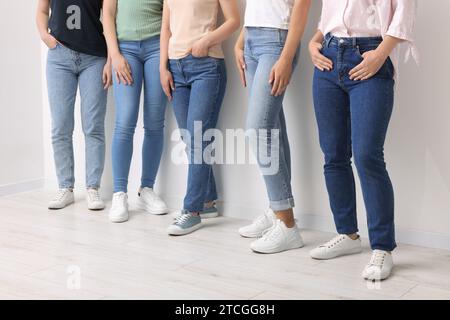 Women in stylish jeans near white wall, closeup Stock Photo
