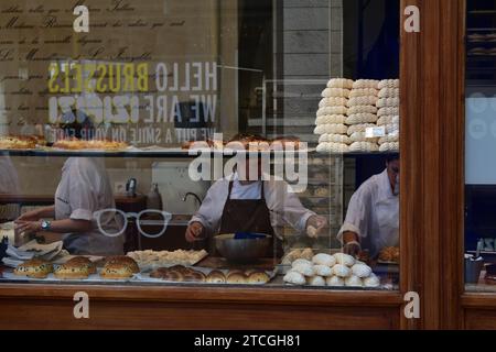 Female pastry chef making pastry goods behind storefront window at the "Aux Merveilleux de Fred" pastry shop in the medieval city centre of Brussels Stock Photo
