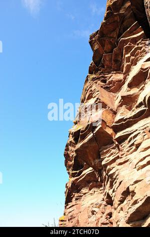A view from below of large, layered red sandstone formations running along the top of the hill. Mountain range Chests, Khakassia, Siberia, Russia. Stock Photo