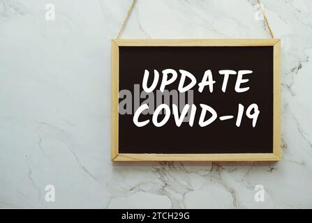 Update Covid-19 typography text on blackboard hanging against on the wall background Stock Photo