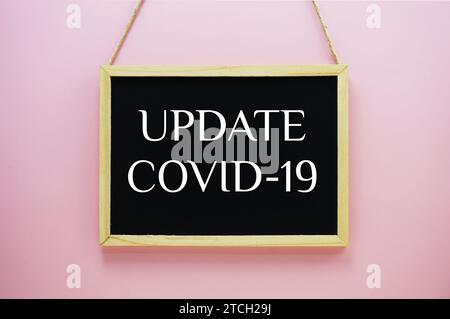 Update Covid-19 typography text on blackboard hanging against on the pink wall background Stock Photo