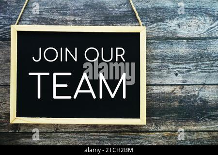 Join Our Team typography text on blackboard hanging against on the wall background Stock Photo