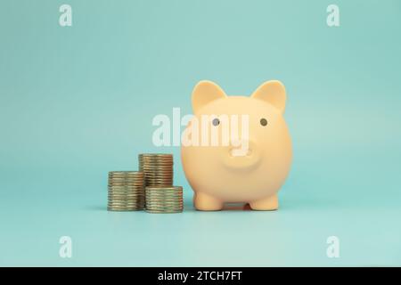 piggy bank on gold coins stack on blue table to save money invest for future. Concept for loan, property ladder, financial, real estate investment, ta Stock Photo