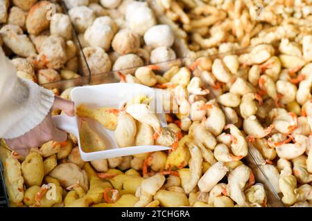 Close up view of people choosing raw or undone tempura shrimp, breaded, crispy, deep fried in batter. Stock Photo