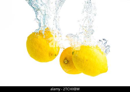 Lemons splash into water and sinking on white background. Tasty and healthy food Stock Photo