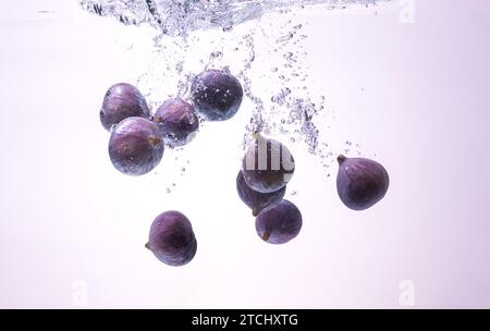 Fresh figs falling into the water isolated on white background. Food photography. Copy space background Stock Photo