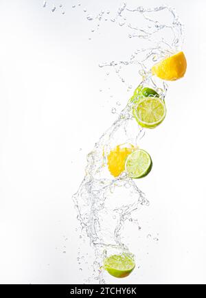 Fresh limes and lemons with water splash in midair, isolated on white background. Refreshment concept Stock Photo