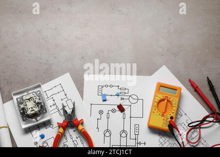 Wiring diagrams, digital multimeter and other electrician's equipment on grey table, top view. Space for text Stock Photo