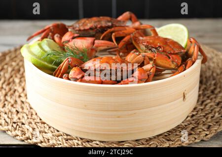 Delicious boiled crabs with lime and dill in bamboo steamer on table, closeup Stock Photo